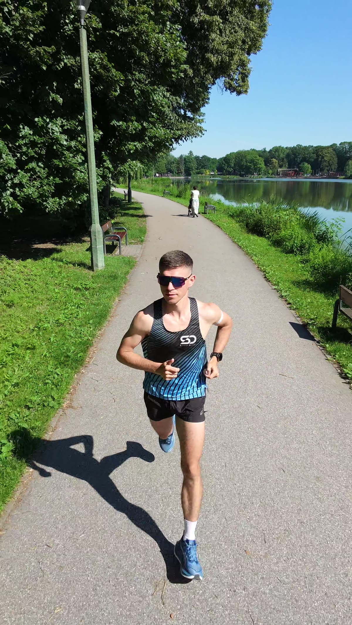 Szymon Dobaj biegnie alejką nad stawem – trening biegowy